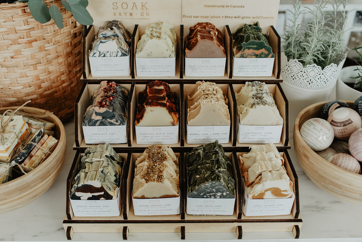 Display of Soak Bath Co. bath bombs in various scents on a white surface with decorative elements.