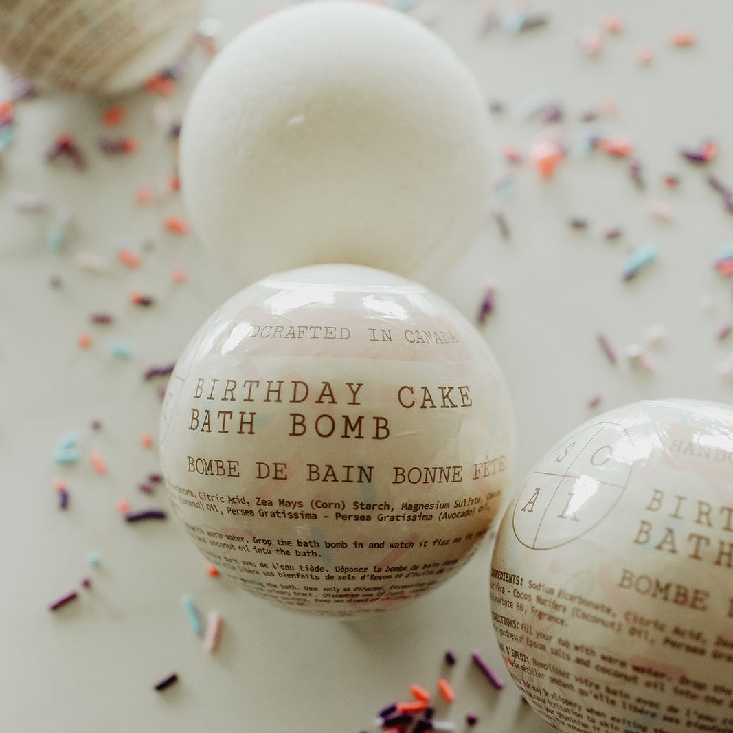 Birthday cake bath bomb with text on a white surface with colorful sprinkles