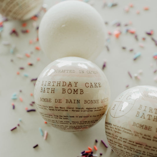Birthday cake bath bomb with text on a white surface with colorful sprinkles