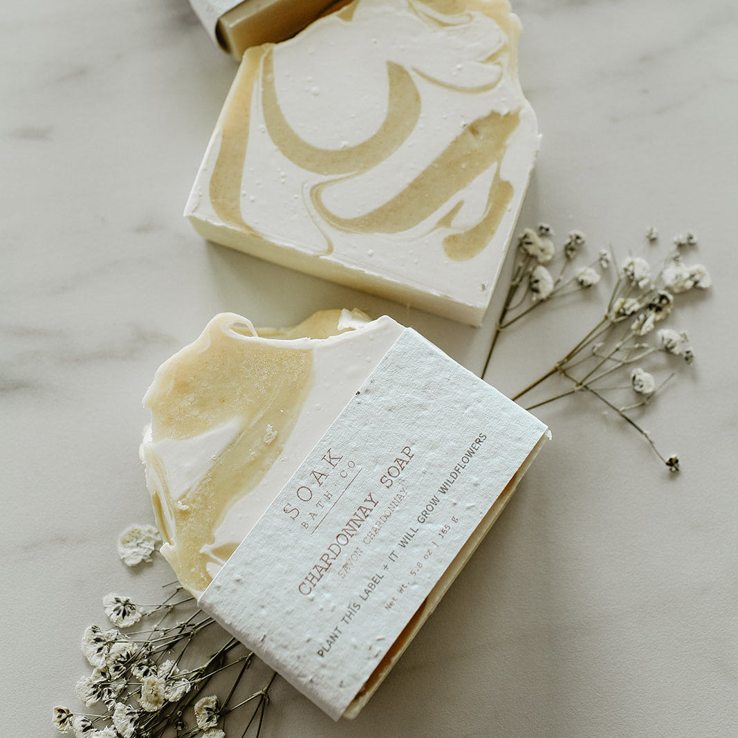Three bars of soap with decorative designs on a marble surface with small white flowers.
