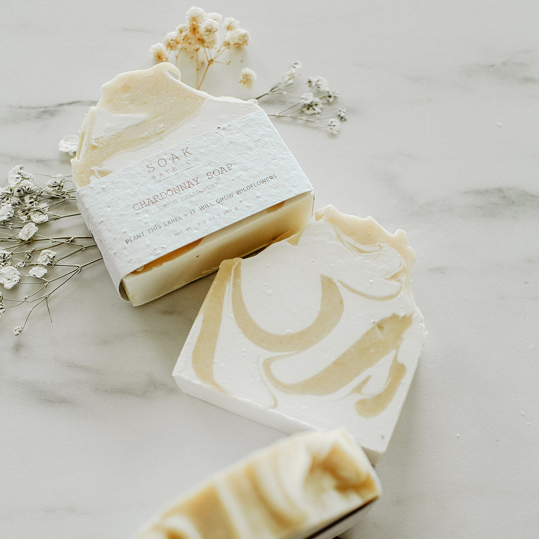 Three bars of soap with decorative designs on a marble surface with small flowers.