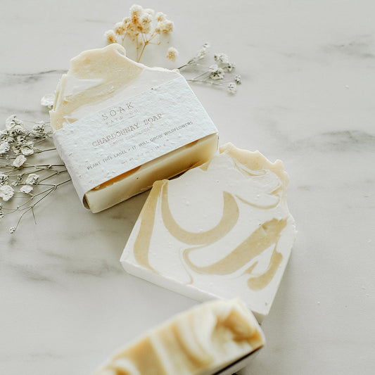 Three bars of soap with decorative designs on a marble surface with small flowers.