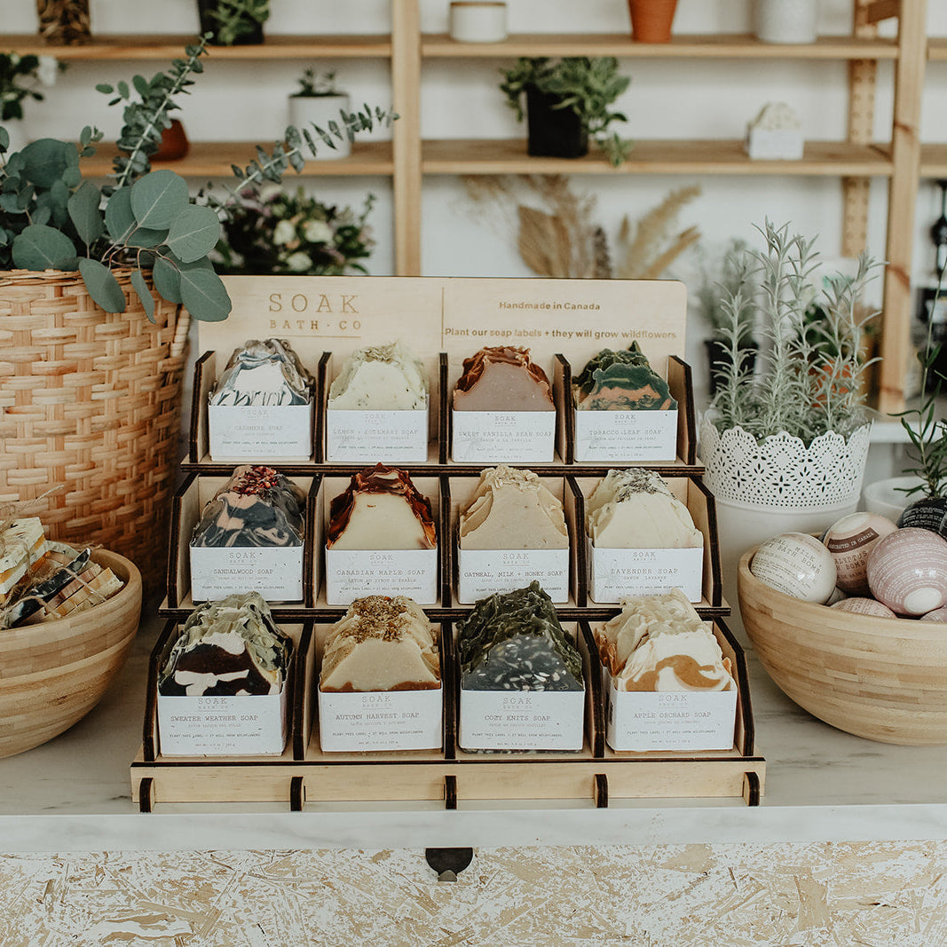 Display of soap bars in a store with plants and shelves in the background