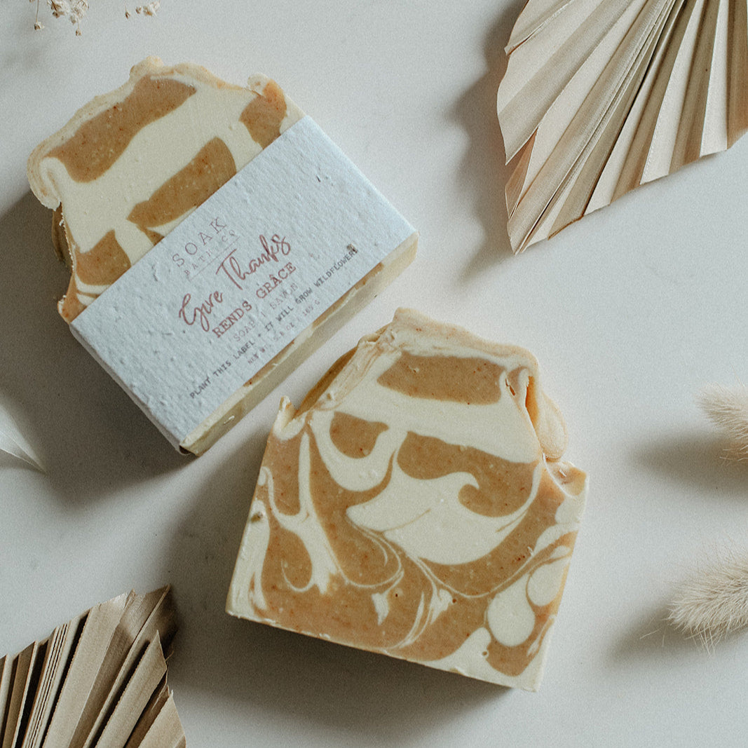 Marbled soap bar with a decorative box on a light surface with dried plants.