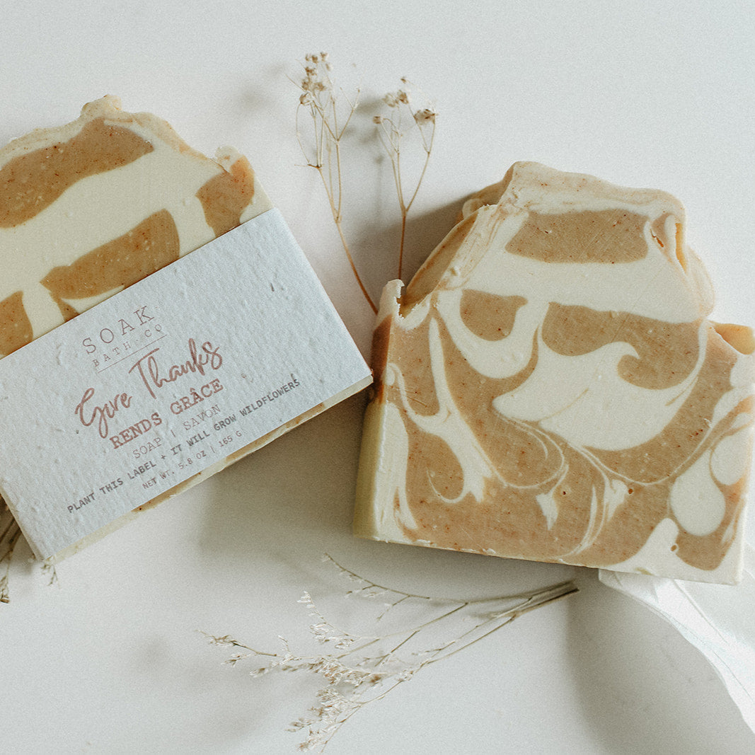 Three bars of soap with a marbled pattern on a white surface with dried leaves.