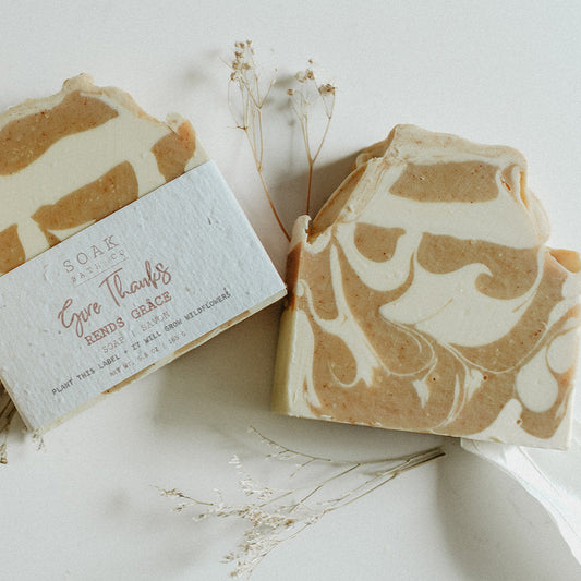 Three bars of soap with a marbled pattern on a white surface with dried leaves.