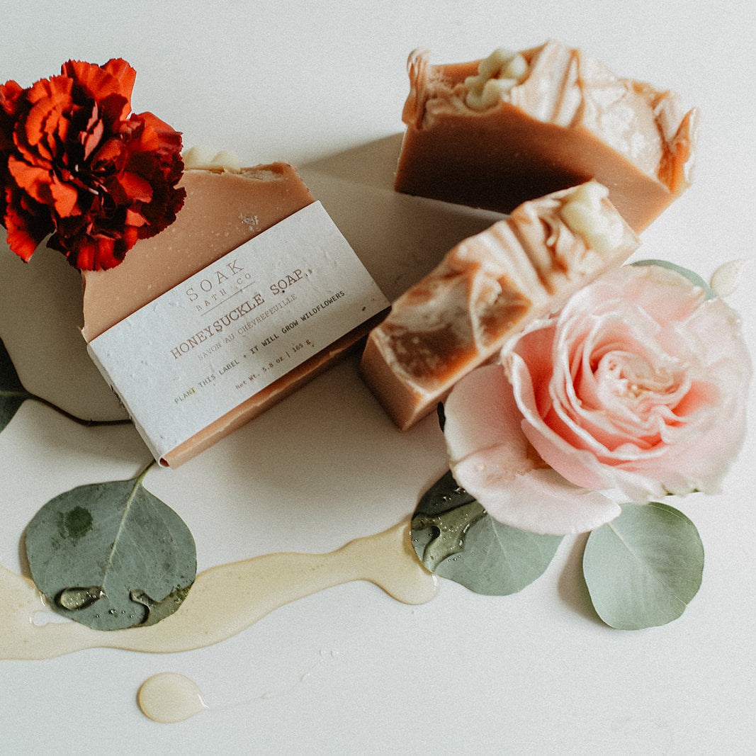 Three bars of soap with flowers and leaves on a light surface