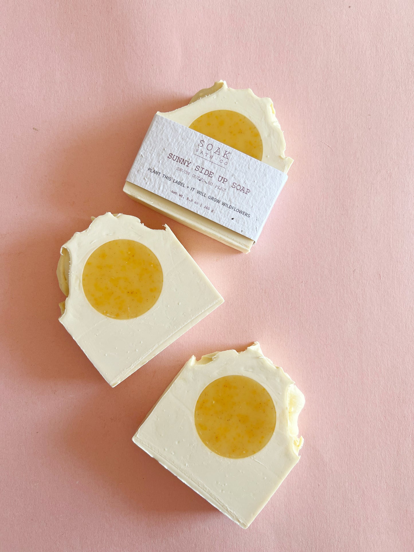 Three bars of soap with a yellow center on a pink background