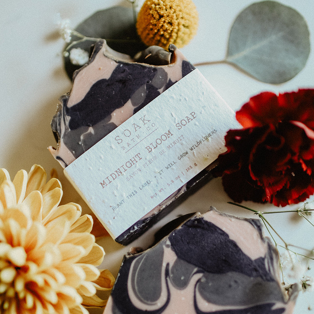 Marbled soap bar with a label on a white surface with flowers and leaves.