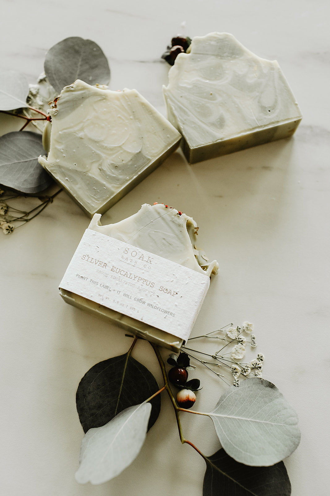 Hexagonal soap bars with a label on a white surface with leaves and flowers.