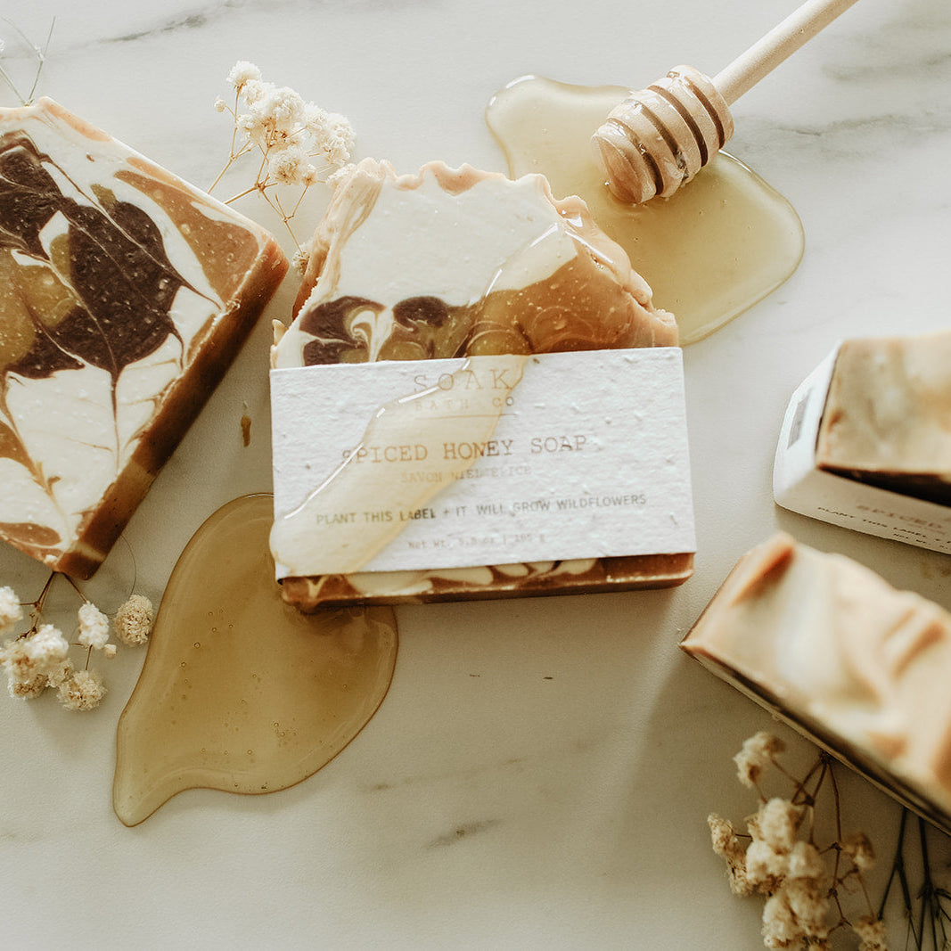 Marble-patterned soap bars with honeycomb and flowers on a marble surface