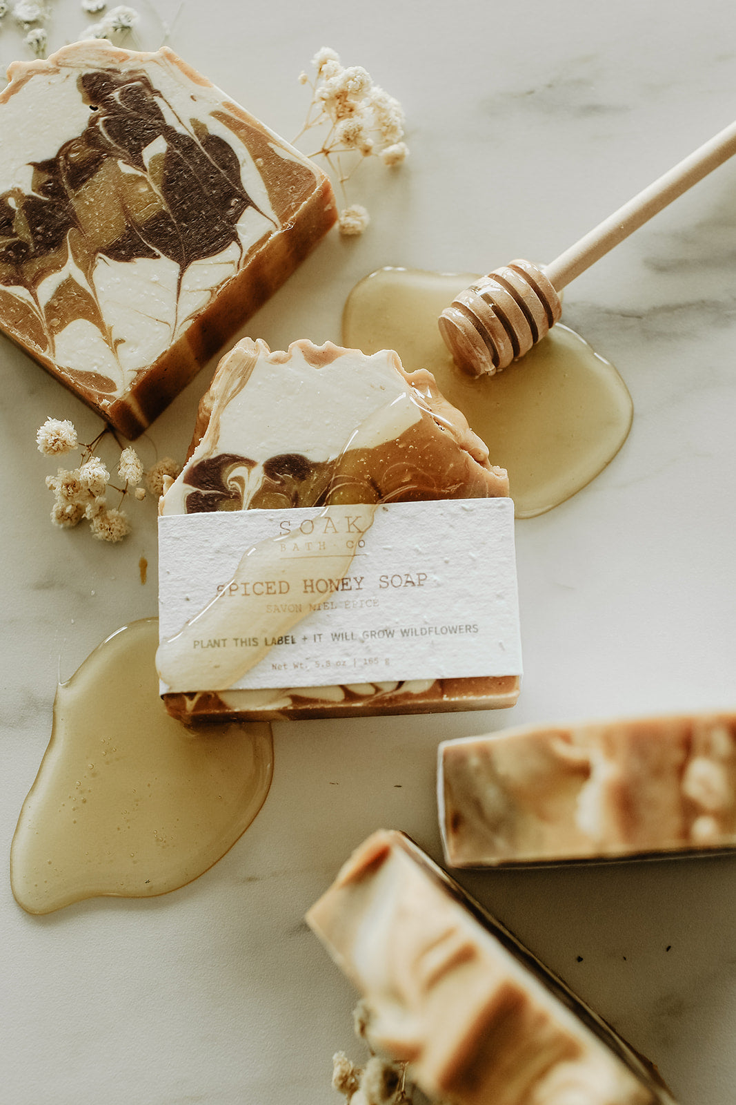 Decorative soap bars with a honeycomb and honey drizzle on a marble surface.