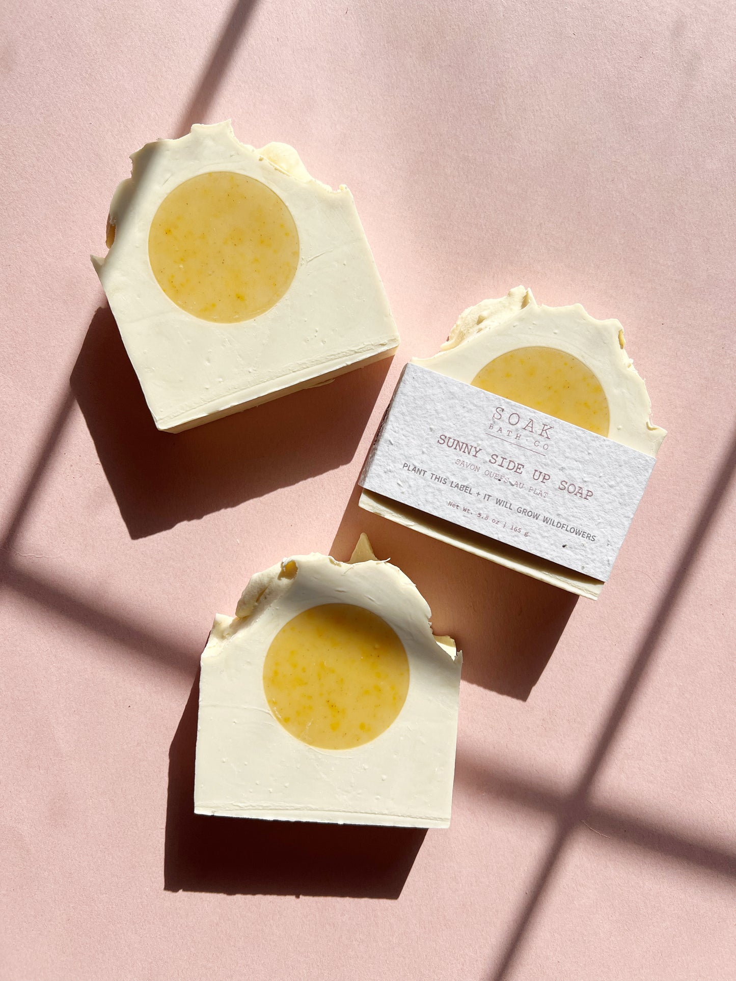 Three soap bars with a circular yellow center on a pink background