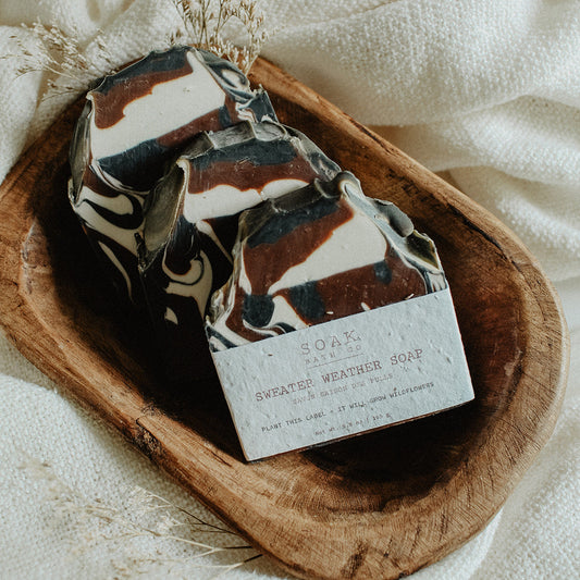 Marbled soap bar with a label on a wooden dish over a white fabric background
