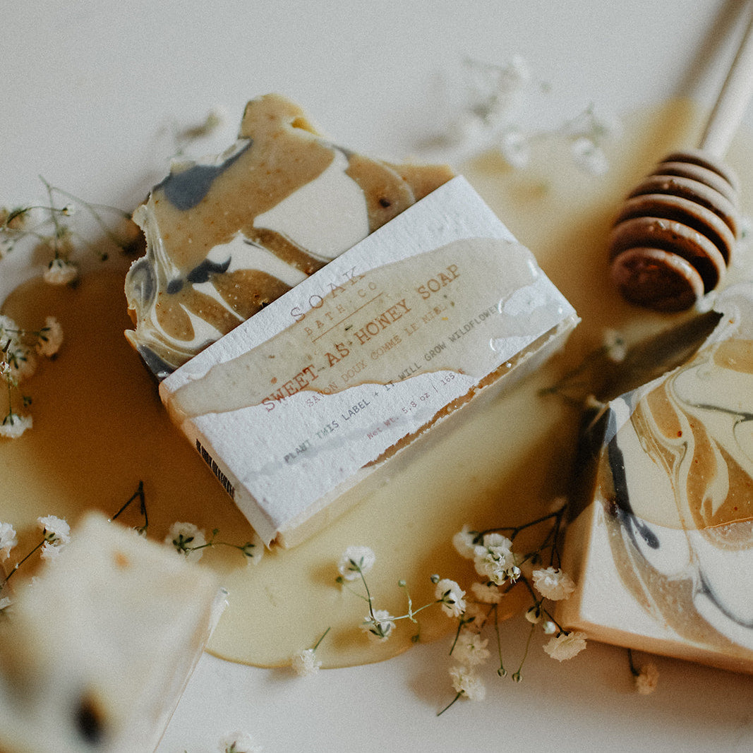 Marble-patterned soap bars with a honey dipper on a light background