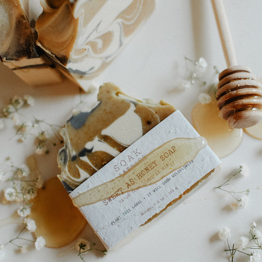 Bar of soap with a honeycomb design, surrounded by small white flowers on a light background.