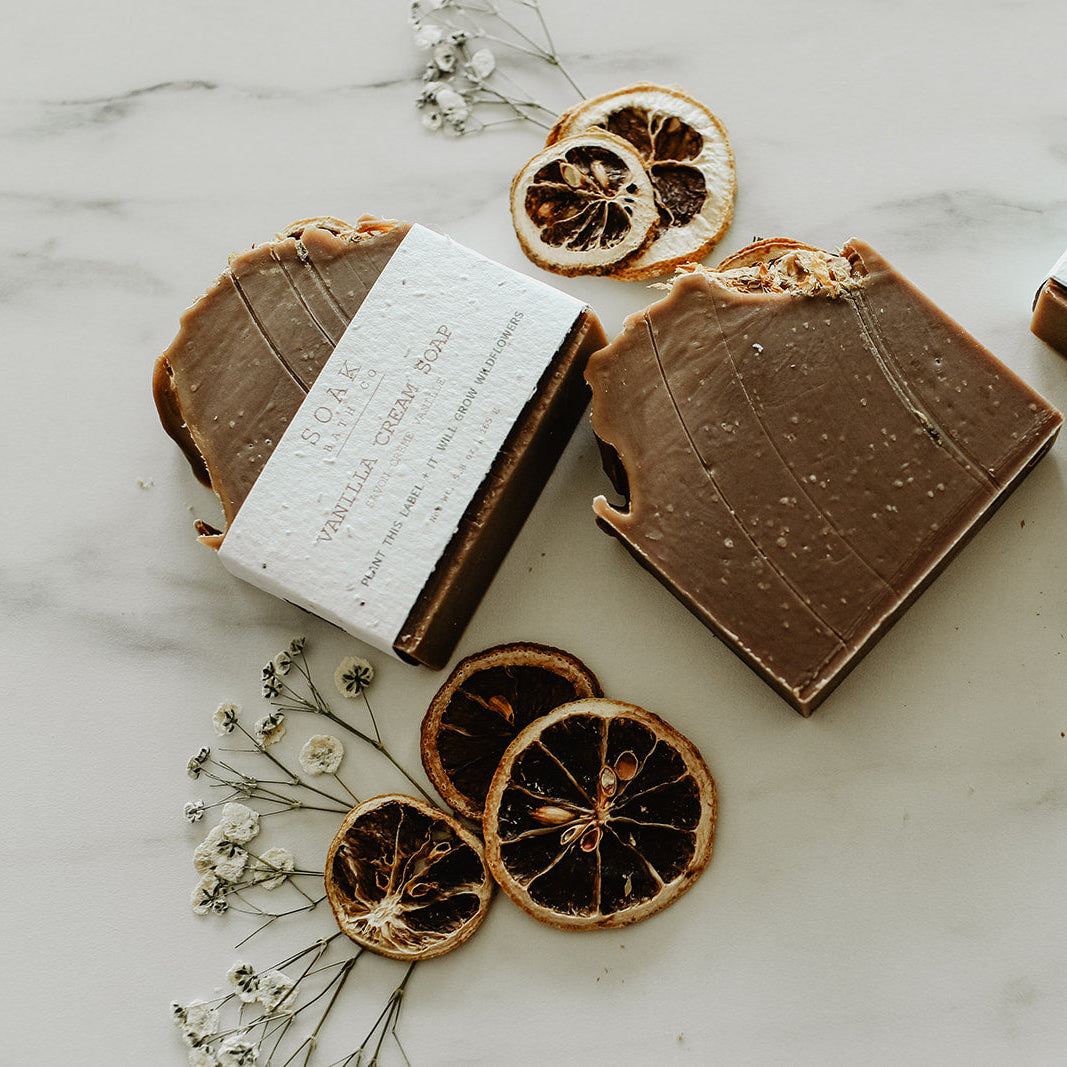 Chocolate bars with white labels on a marble surface with dried oranges and flowers.