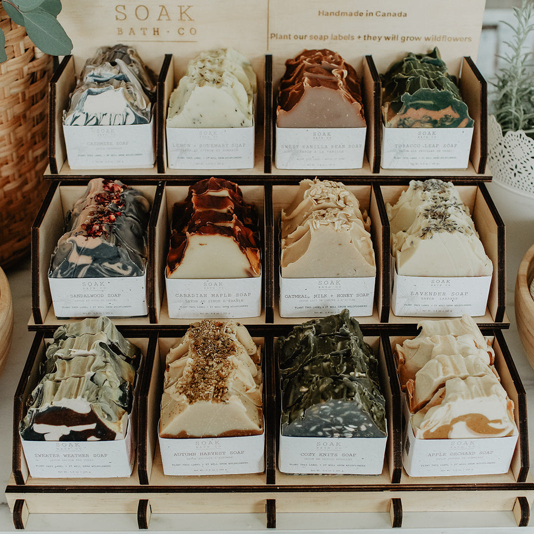 Display of Soak Bath Co. bath bombs in various scents on a white surface with decorative elements.